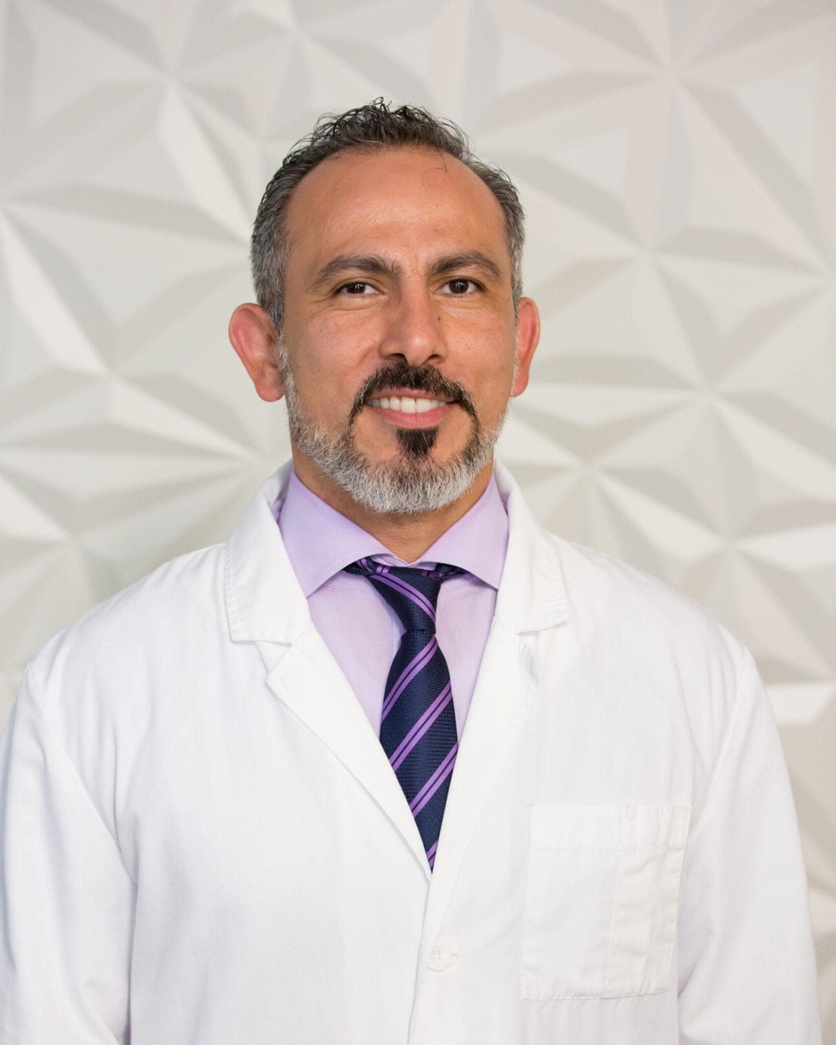A dentist of the practice, smiling, in a white coat
