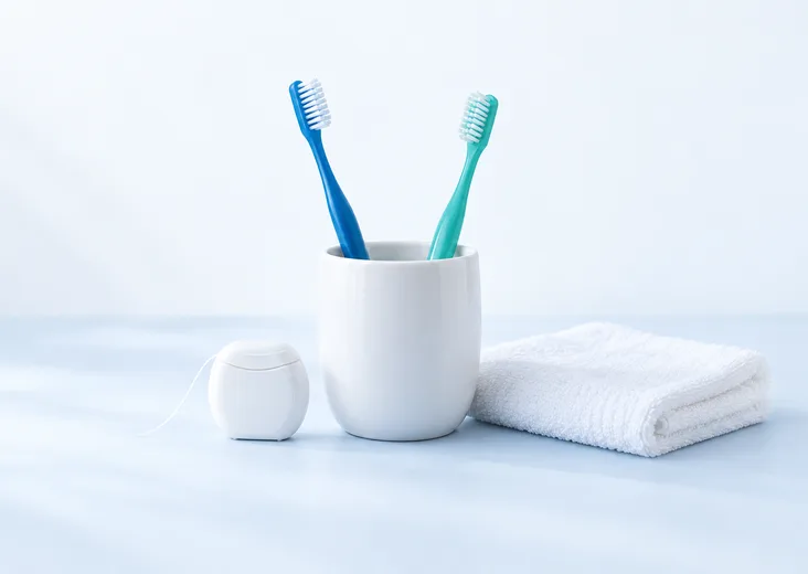 Blue and teal toothbrushes with floss and a white towel.